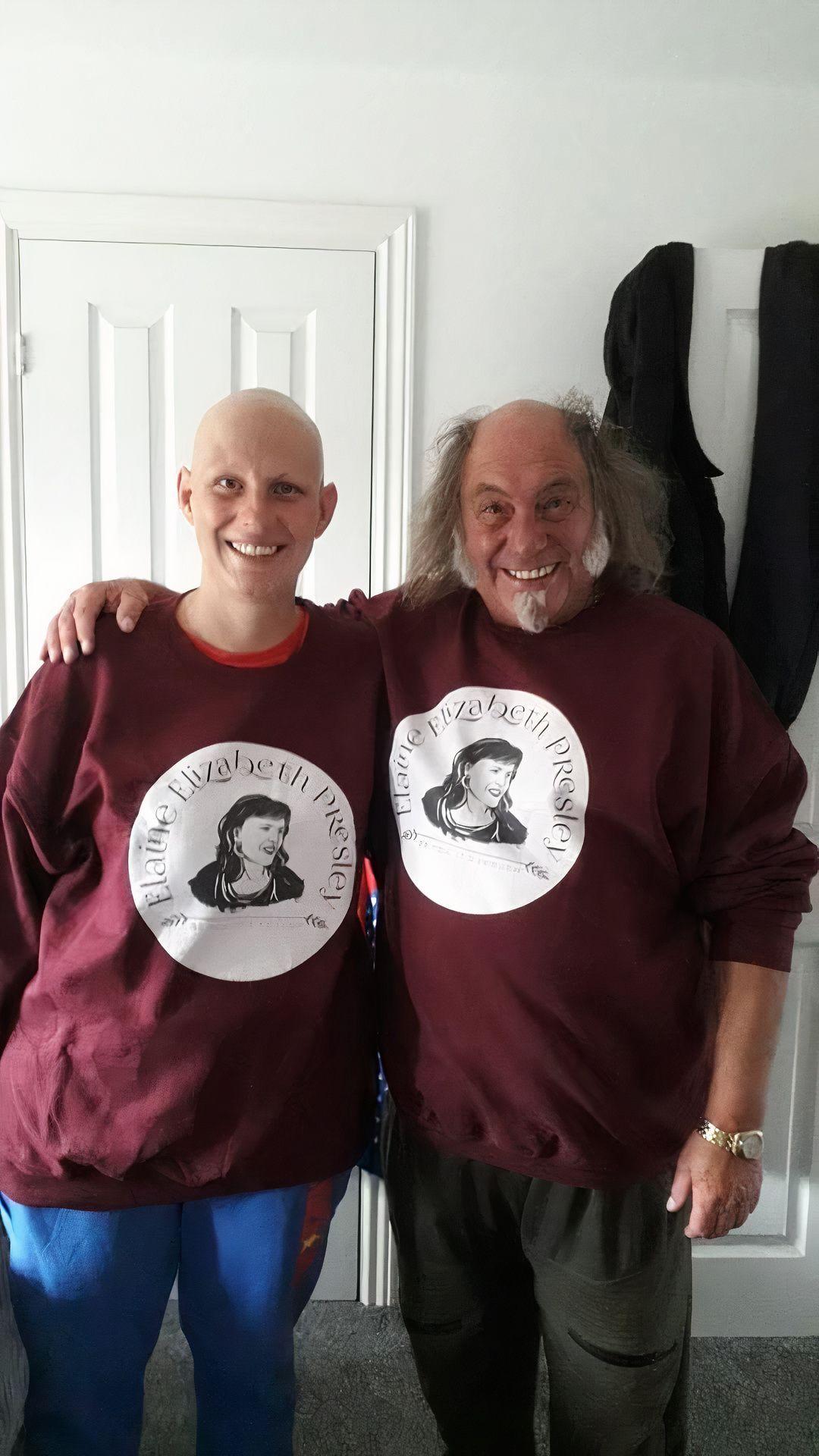 Two individuals standing close together wearing matching maroon sweatshirts with a circular graphic and text.